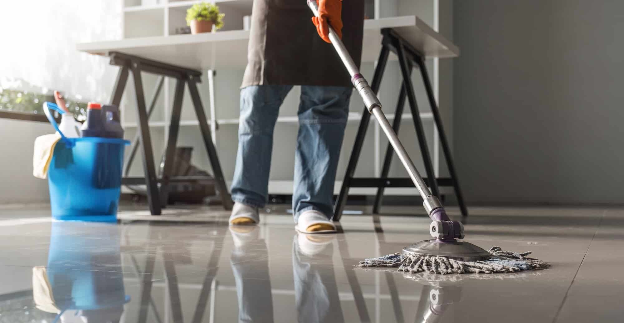 Cleaning in the office Beautiful cleaning lady uses a mop and a vacuum cleaner to clean the floor